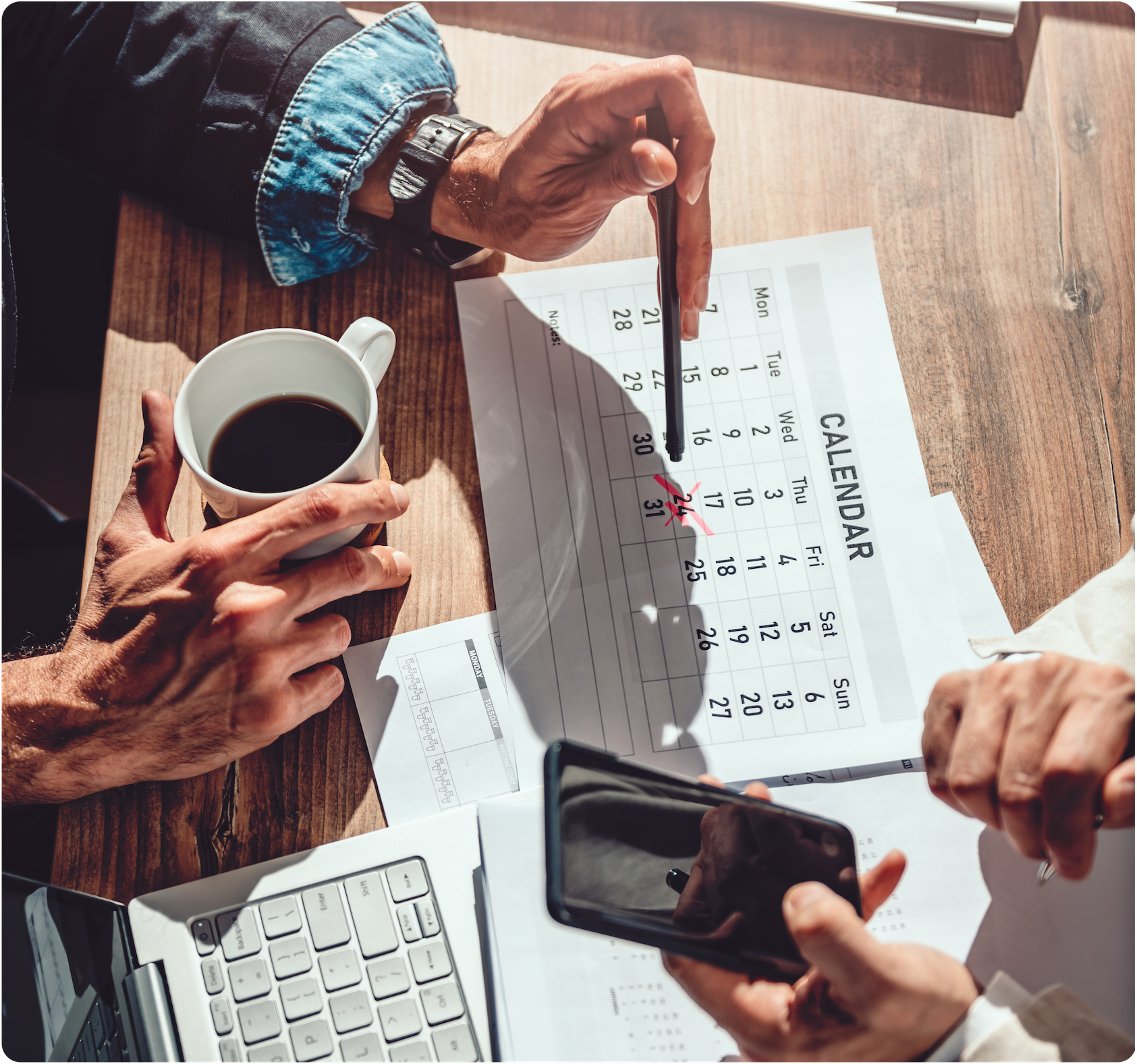 Top-down photo of two people sitting at table working on a calendar and a phone