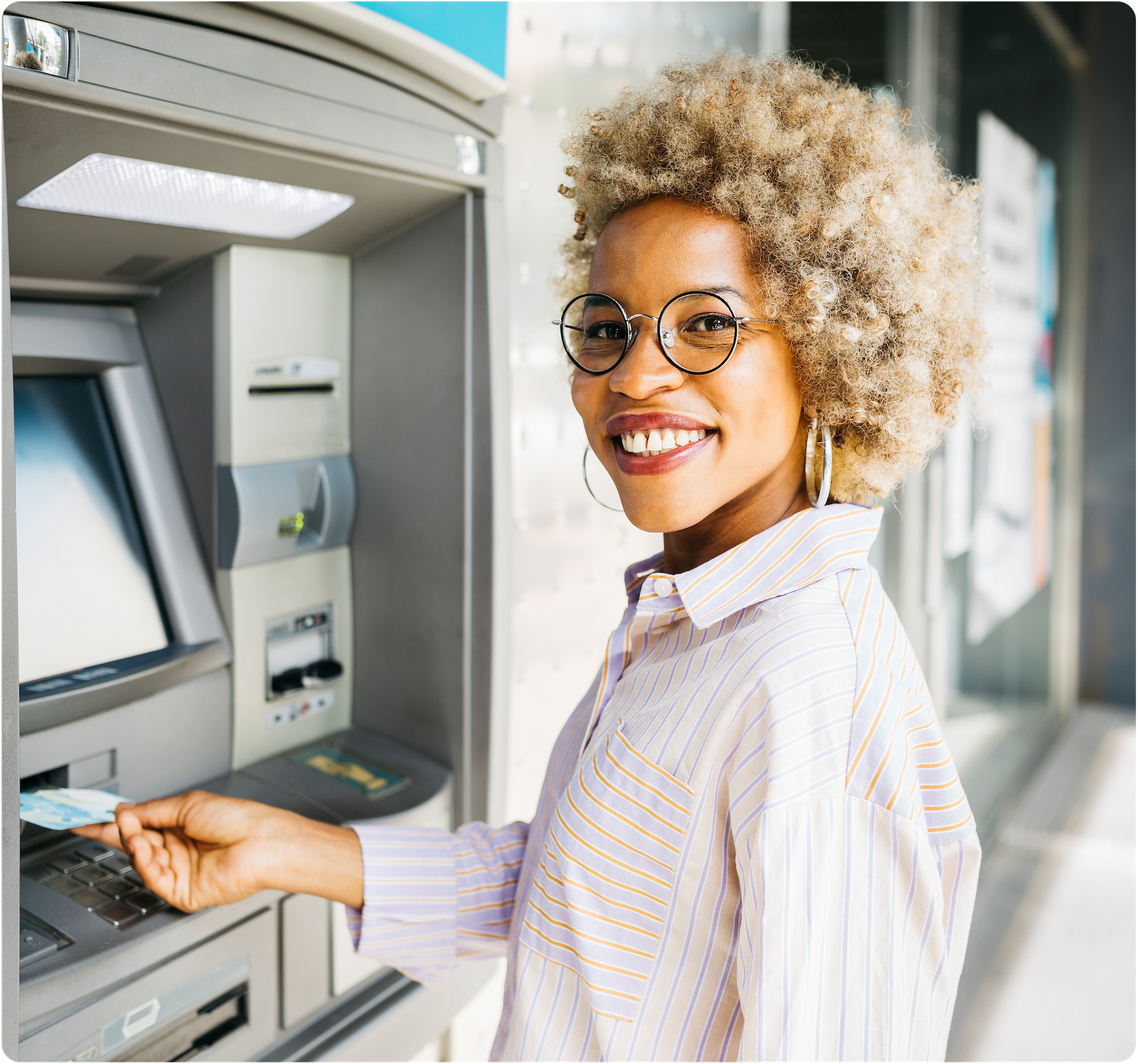 Smiling woman inserting card into ATM